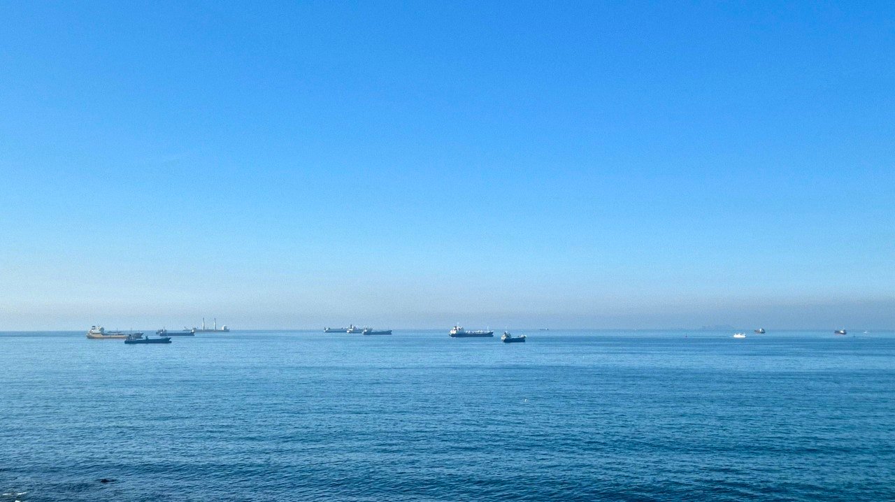 Cargo ships anchored off the coast near Busan under a clear blue sky
