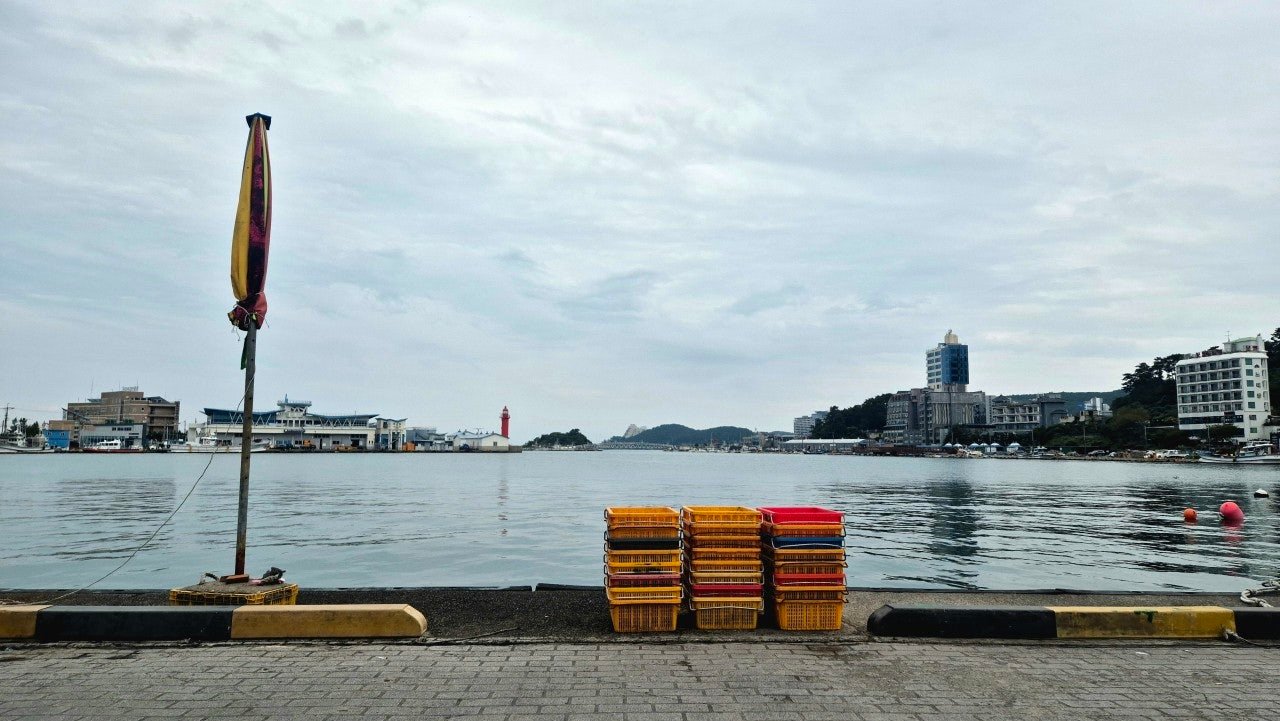Quiet morning view of Daebyeon Port harbor near Gijang, Busan, with fish crates on the dock