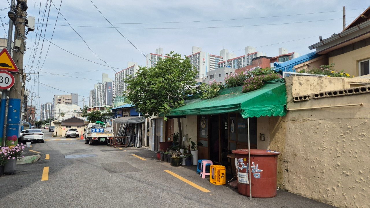 Quiet neighborhood street near Gaegeum Station, Busan, with apartment towers in the background