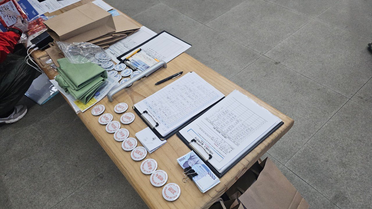 Trailhead sign-in table with badges and donation box at the start of Gamnaetgil Course 1-1, Gijang, Busan