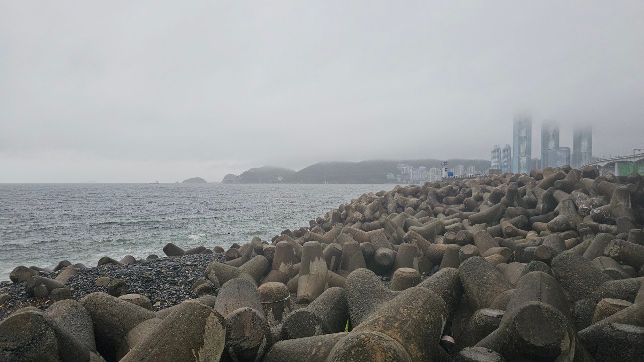Foggy tetrapod breakwater coastline with Busan skyline barely visible, Gamnaetgil Course 10