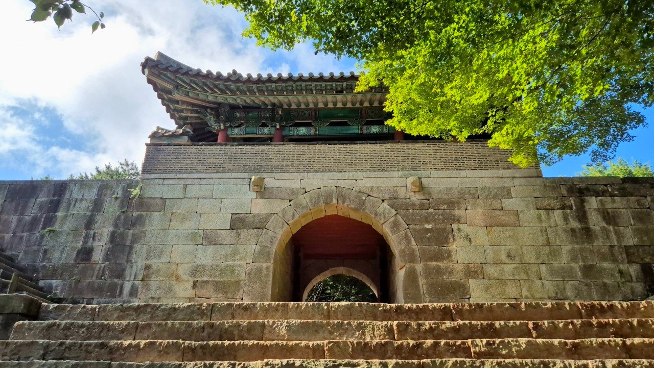 Stone arch gate of Geumjeongsanseong Fortress in Busan, framed by green trees