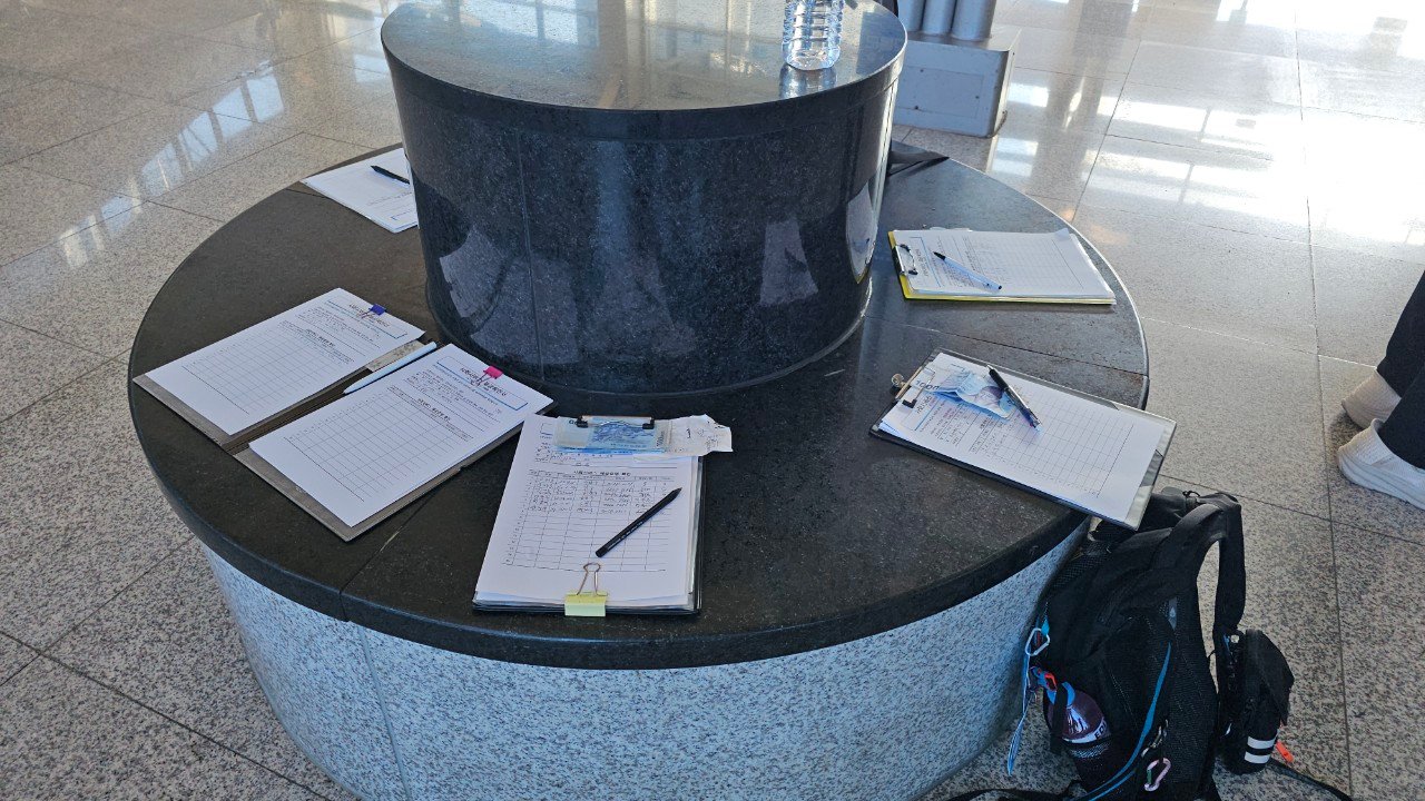 Round marble meeting table with sign-in clipboards and paperwork at Gupo Station, Busan